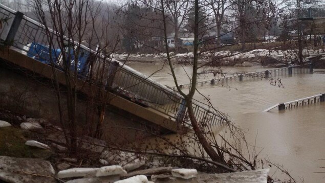 Un camion bloqué sur un pont effondré dans une rivière. Un camion bloqué sur un pont effondré dans une rivière.