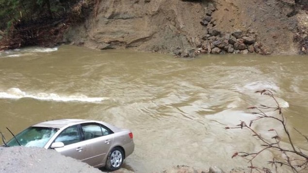 Un véhicule au fond d'un trou béant laissé par un ponceau qui a cédé.