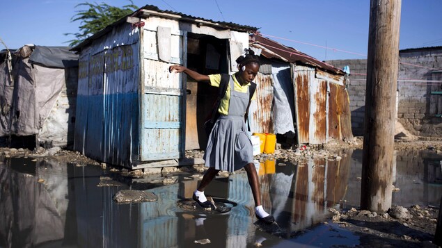 Une étudiante dans son uniforme scolaire se balance sur des pierres au-dessus des eaux usées Une étudiante dans son uniforme scolaire se balance sur des pierres au-dessus des eaux usées