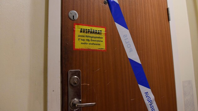 Une porte sur laquelle des policiers ont posé un ruban bleu et blanc et un avertissement.