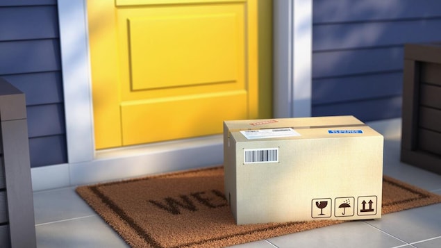 Une boite de livraison déposée devant une porte jaune extérieur. 