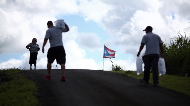 Une femme attend pendant que des employés municipaux distribuent l'eau et la glace après le passage de l'ouragan Maria sur l'île en septembre 2017, à Comerio, à Porto Rico, le 31 janvier 2018. Une femme attend pendant que des employés municipaux distribuent l'eau et la glace après le passage de l'ouragan Maria sur l'île en septembre 2017, à Comerio, à Porto Rico, le 31 janvier 2018.
