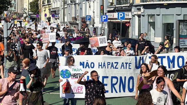 Une rue de Lisbonne avec des manifestants munis de pancartes et de banderoles.