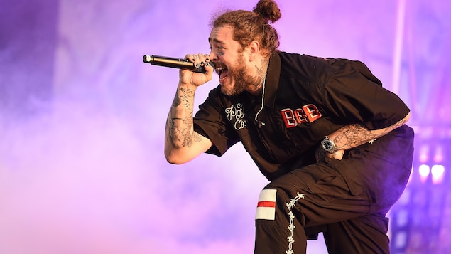 Le chanteur est penché et tient un micro dans sa main en chantant.