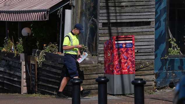 A postal worker walking near a mailbox.