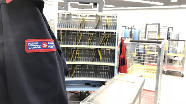 Un manteau de facteur en premier plan, un centre de distribution en arrière-plan. Un manteau de facteur en premier plan, un centre de distribution en arrière-plan.