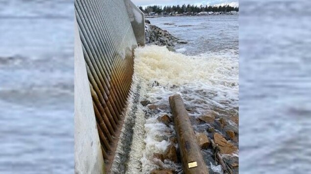 Un poteau électrique échoué sur des roches dans l'eau.