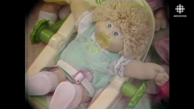 Une poupée Bout d'Chou avec une suce dans un petit transat jouet.