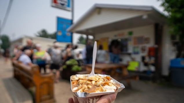 Une main tient une poutine.