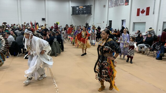Des Autochtones en tenue traditionnelle dans une grande salle.