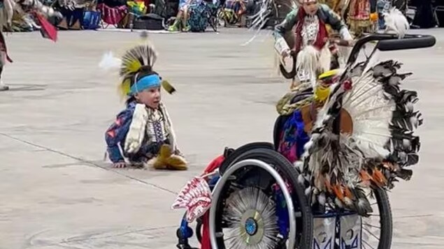 Un enfant habillé en habit traditionnel autochtone participe à un pow-wow.