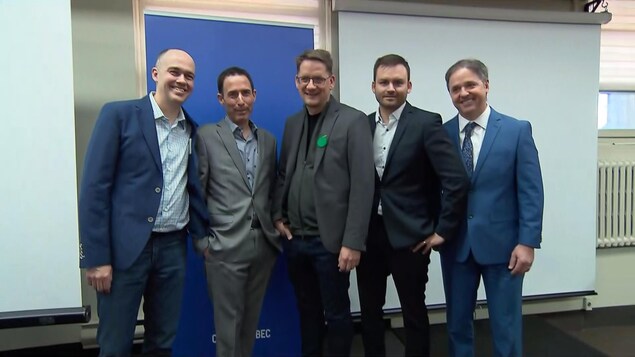 Cinq hommes en veston et cravate sourient à la caméra.