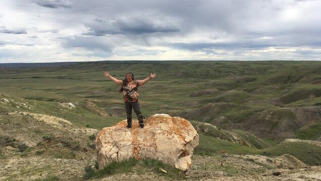 Joely BigEagle-Kequahtooway bras au ciel, sur un rocher, dans le Parc national des Prairies.