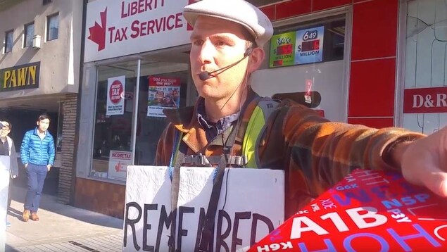 Un homme est accoté sur une boîte postale avec un micro dans la rue. Un homme est accoté sur une boîte postale avec un micro dans la rue.