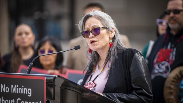 Une femme parle à un lutrin.