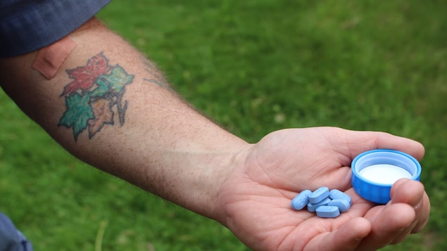 Un homme a des pilules bleues dans les mains.