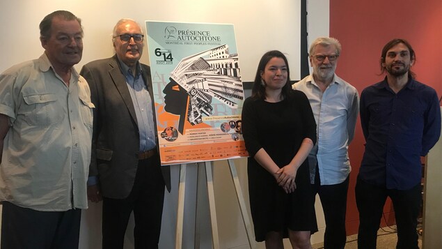 Cinq personnes posent avec l'affiche du festival Présence autochtone.