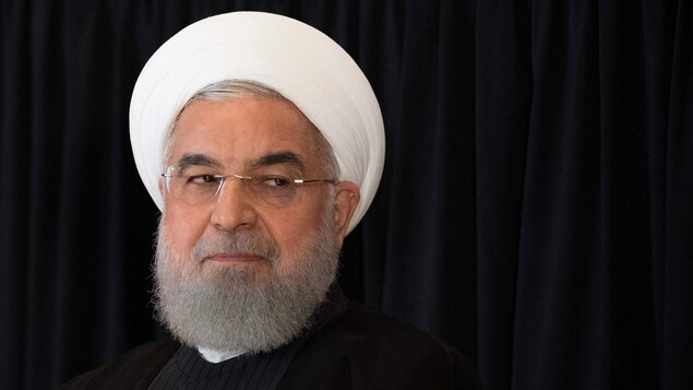 Un homme à la barbe mi-longue porte des lunettes ainsi qu'un couvre-chef qui signifie sa position dans la hiérarchie iranienne. Il regarde de biais, vers sa gauche.