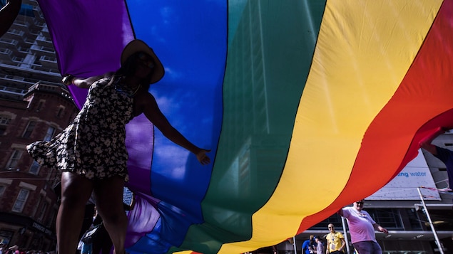 Isang babae sa ilalim ng 2SLGBTQ+ na bandila.