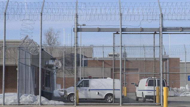 Des véhicules sont stationnés derrière les grilles de la prison.