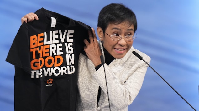 Hawak ni Maria Ressa ang branded t-shirt na may nakasulat na "Believe there is good in the world."