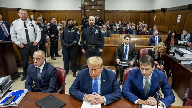 Vue du tribunal avec à l'avant-plan Donald Trump, les yeux fermés, et ses avocats.