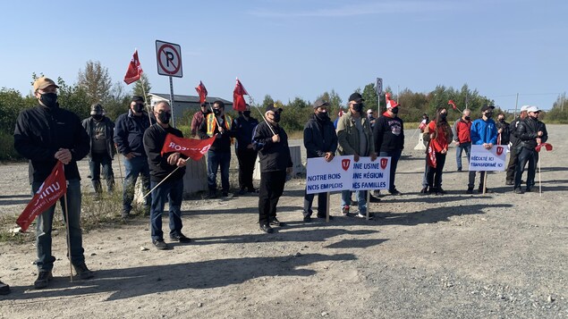 Une vingtaine de personnes portant un masque écoutent les discours.