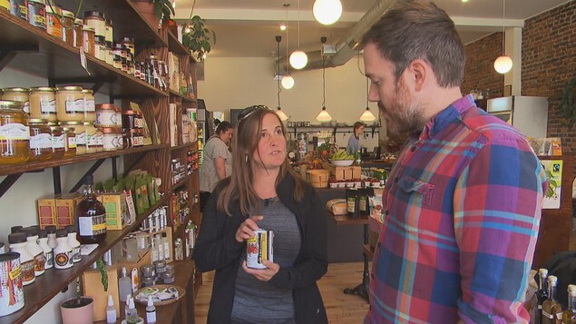 Stéphanie Dufresne inspecte une canne de sirop d'érable en compagnie du propriétaire du marché Notre-Dame