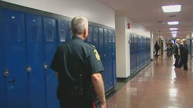 Un policier marche dans le couloir d'une école. 