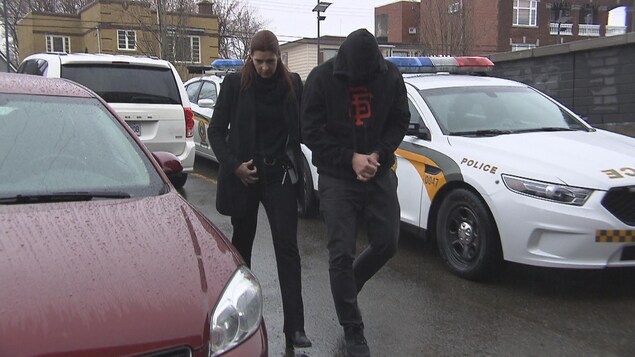 Un homme se cache le visage à son arrivée au palais de justice.