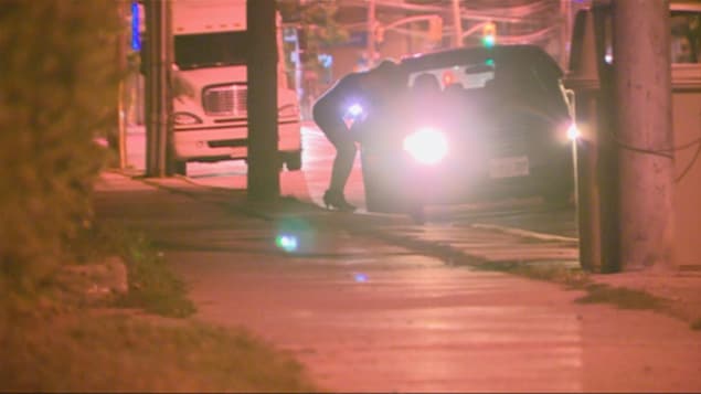 Une prostituée parle à un automobiliste le long de la rue