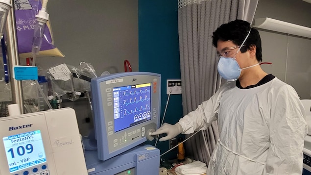 Un docteur portant un masque et surveillant un moniteur, à l'hôpital