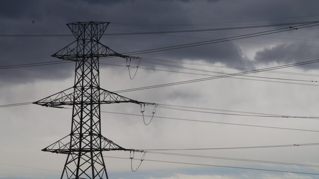 Pylône d'électricité avec des nuages menaçants en arrière-plan.