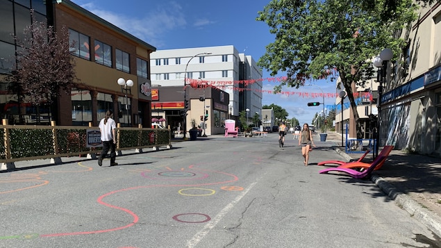Des passants marchent sur la rue Perreault, décorée.