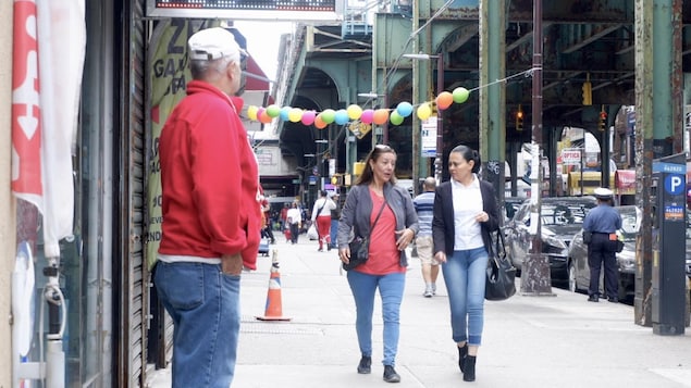 Deux femmes marchent sur un trottoir dans une grande ville américaine.