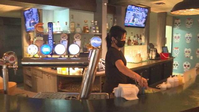 Une femme derrière le bar.