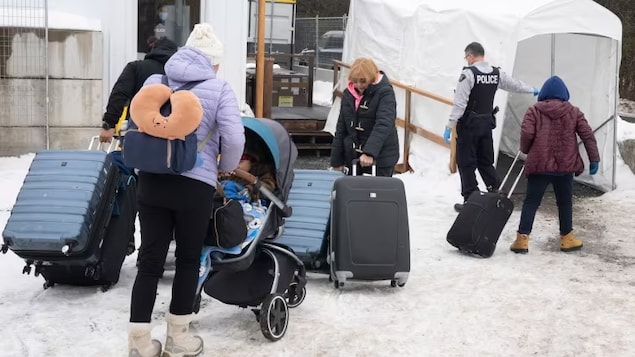Une famille de demandeurs d'asile de la Colombie est accueillie par un agent de la GRC au chemin Roxham le 9 février. (Ryan Remiorz, La Presse canadienne)