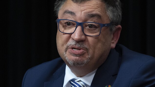 Horacio Arruda en point de presse sur un fond noir.