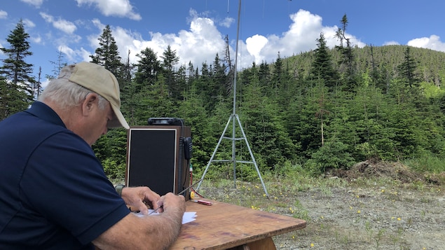 Un homme devant ses instruments radio en montagne.