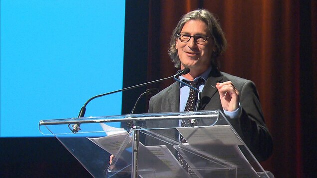 Jean-René Dufort parle derrière un lutrin.