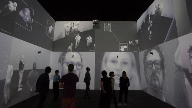 Des personnes regardent des images d'eux-mêmes sur un mur. Des personnes regardent des images d'eux-mêmes sur un mur.