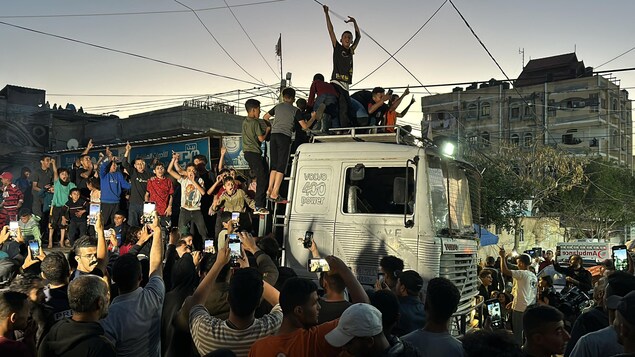 Des Palestiniens rassemblés autour et sur une camionnette lèvent les bras en l'air.