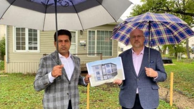 Le promoteur immobilier Rahul Kumar et l'ancien conseiller municipal de Winnipeg Russ Wyatt posent devant la maison qui devait être convertie en habitation qui comporterait six unités.