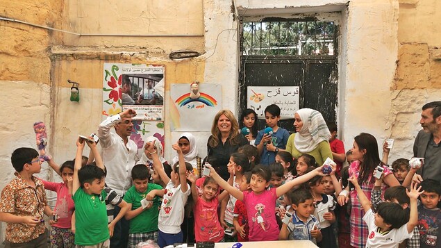 Les enfants réfugiés syriens lèvent les bras de joie après avoir reçu leurs radios.