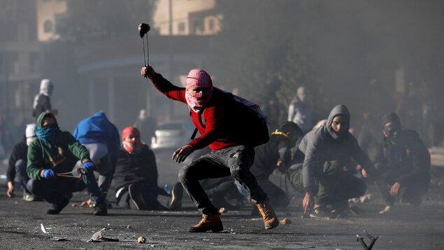 Des manifestants palestinens avec des pierres dans une rue.