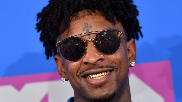 21 Savage porte des lunettes de soleil et a des dents en or. 