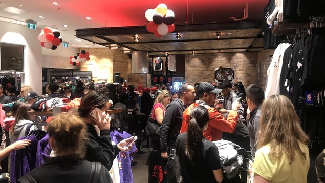 Des gens sont dans un magasin de sport aux couleurs des Raptors.