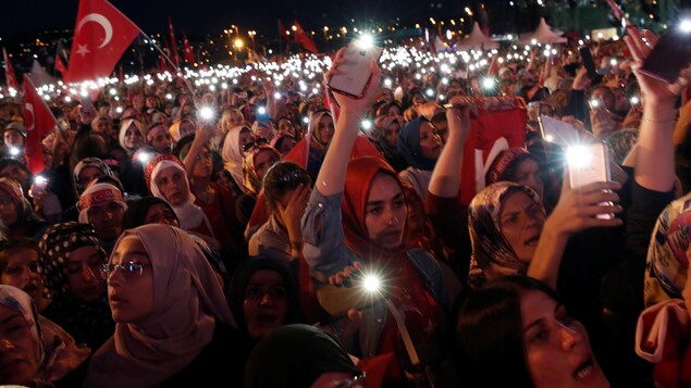 Une foule de personnes brandissant des drapeaux turcs et leur cellulaire avec le flash allumé dans la nuit Une foule de personnes brandissant des drapeaux turcs et leur cellulaire avec le flash allumé dans la nuit