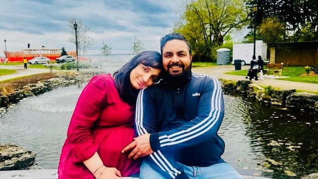 Le couple pris en photo sur un banc devant un étang. 
