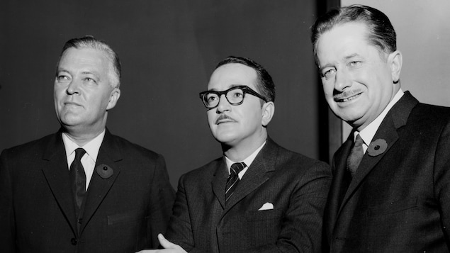 Le modérateur Raymond Charette, posant entre le chef du Parti libéral du Québec, Jean Lesage et le chef de l'Union nationale, Daniel Johnson. Le modérateur Raymond Charette, posant entre le chef du Parti libéral du Québec, Jean Lesage et le chef de l'Union nationale, Daniel Johnson.